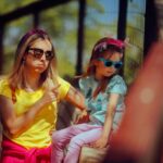 Une mère en t-shirt jaune donne des consignes à sa fille portant des lunettes de soleil.
