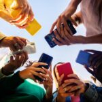 Groupe de jeunes regardant leur téléphone, pris en contre-plongée.