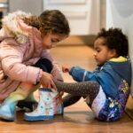 Enfants s'entraidant pour mettre des bottes