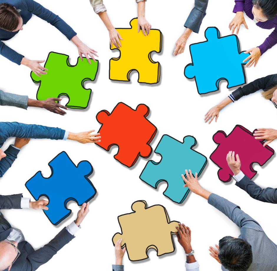 Des mains de plusieurs personnes tenant des pièces de puzzle colorées