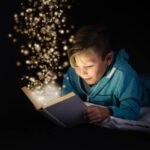 Un enfant lis un livre duquel sortent des paillettes