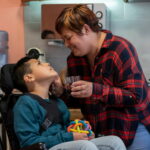 Une mère et son fils en situation de handicap en fauteuil se regardent tendrement